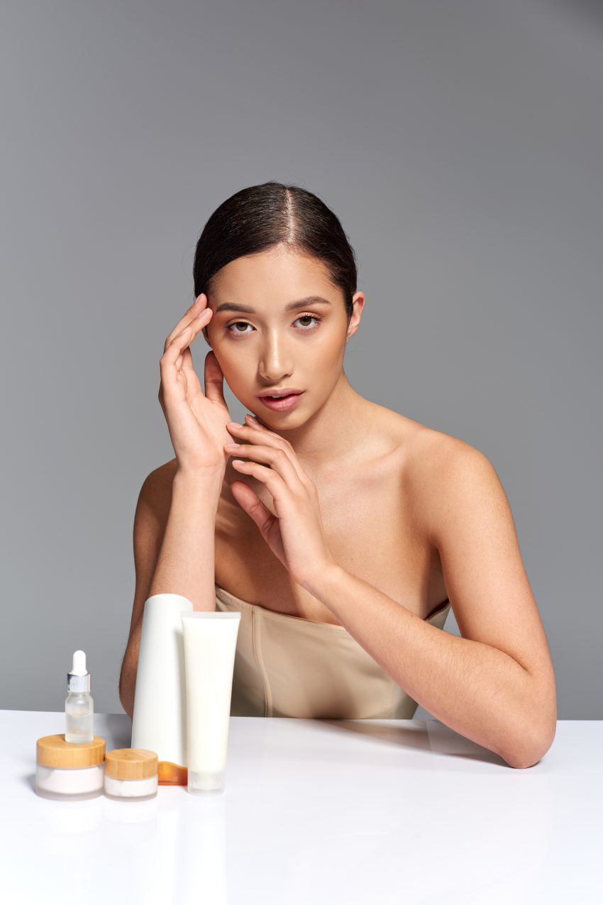 beauty industry, skin care, young asian woman with brunette hair posing near beauty products