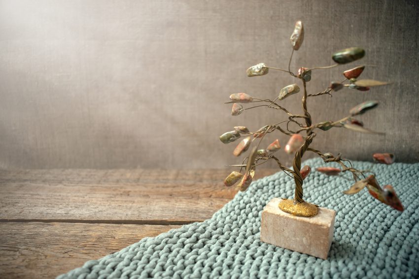 Jasper and wire tree in the rays of light on knitted fabric and old vintage textured wooden